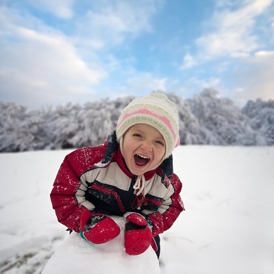 Child playing in snow with blurred background