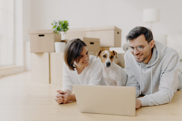 A man, woman and dog looking at a laptop